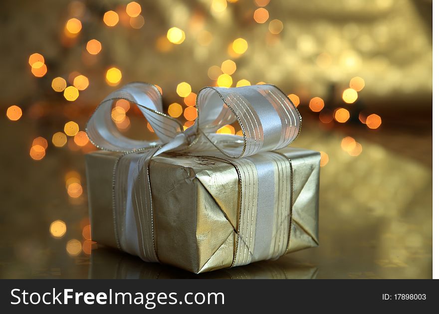 Gift box and blured lights on golden background.