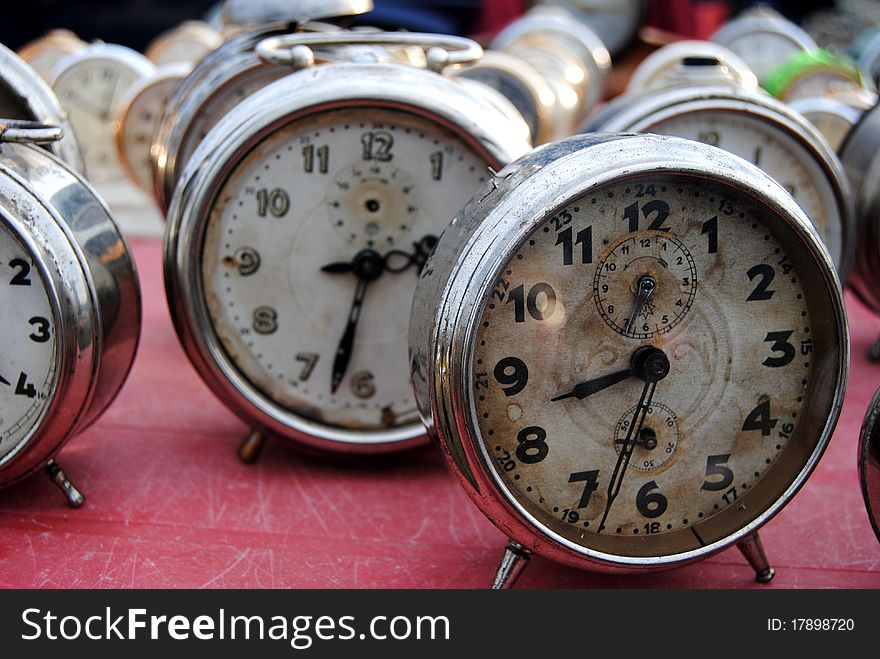 A photograph of antique clocks at an open-air antique market. A photograph of antique clocks at an open-air antique market