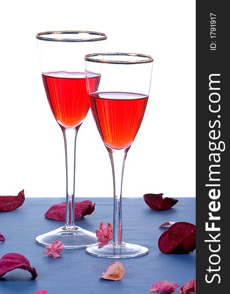 Two glasses of wine on table with rose petals on white background. Two glasses of wine on table with rose petals on white background