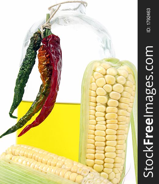 Bottle of yellow oil and fresh corn on the cob with pepper