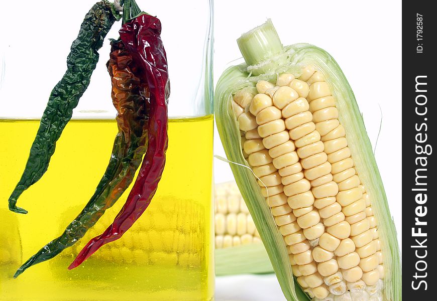 Bottle of yellow oil and fresh corn on the cob with pepper