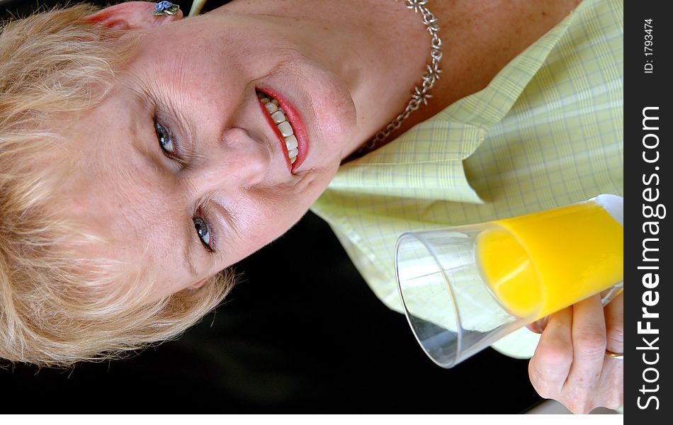 A senior woman holding a glass of orange juice. A senior woman holding a glass of orange juice