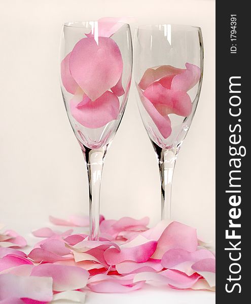 Pink and white rose petals surrounding two wine glasses. Pink and white rose petals surrounding two wine glasses