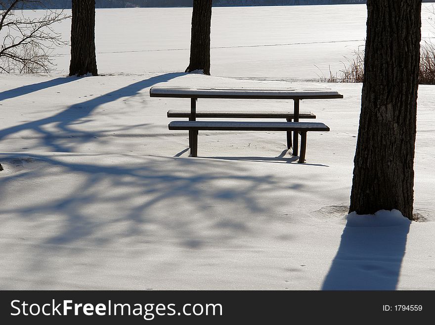 A picnic table sits quietly in the winter snow. A picnic table sits quietly in the winter snow.