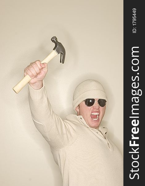 Man with wool sweater and wool hat holds up a hammer in sign of strength. Man with wool sweater and wool hat holds up a hammer in sign of strength