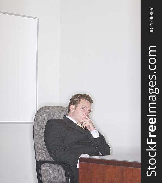 Businessman sitting in his chair with his hand on his chin thinking in his office