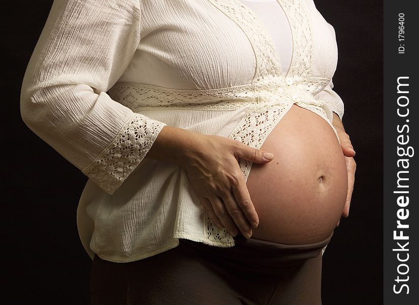 A very pregnant Mom shows her tummy for portrait session. A very pregnant Mom shows her tummy for portrait session.