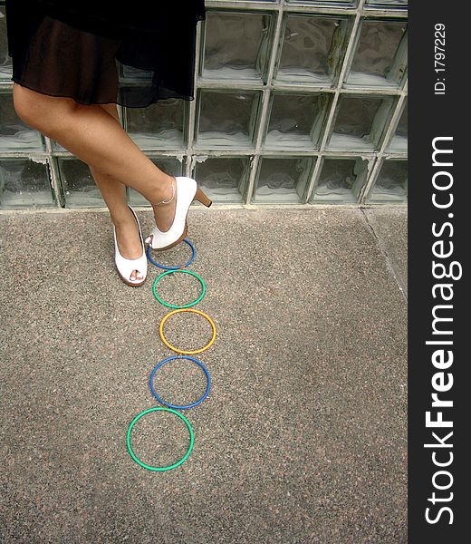 Feet with heels standing next to a row of colored rings