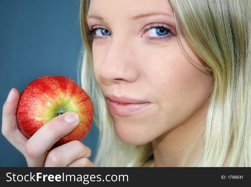 A smiling young blond woman is holding a apple in her hand. A smiling young blond woman is holding a apple in her hand