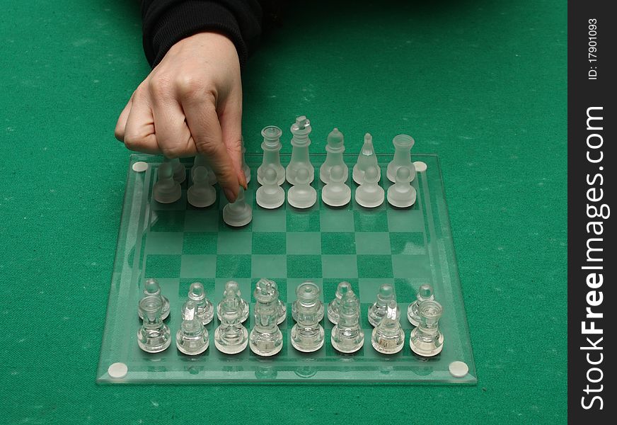 A female hand making the first move on a chess match. A female hand making the first move on a chess match.