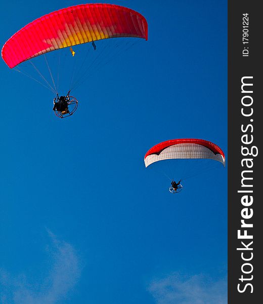 A Paraglider flies in the blue sky