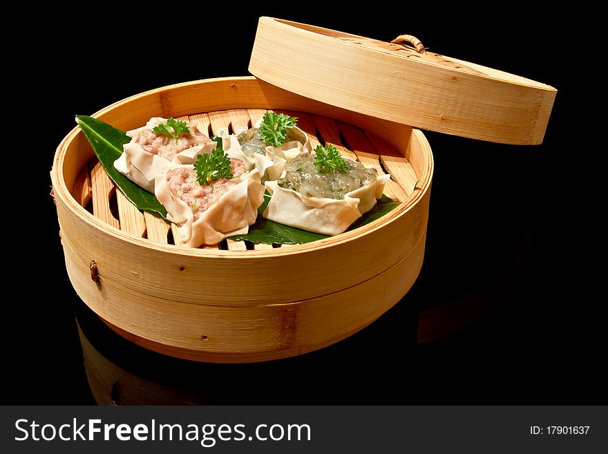 Dim Sums in bamboo basket on black