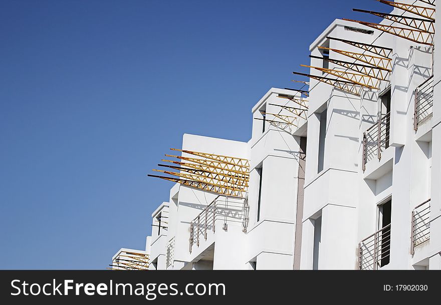 This capture is of an residential apartment complex, under construction, against a blue sky in the background. This capture is of an residential apartment complex, under construction, against a blue sky in the background.