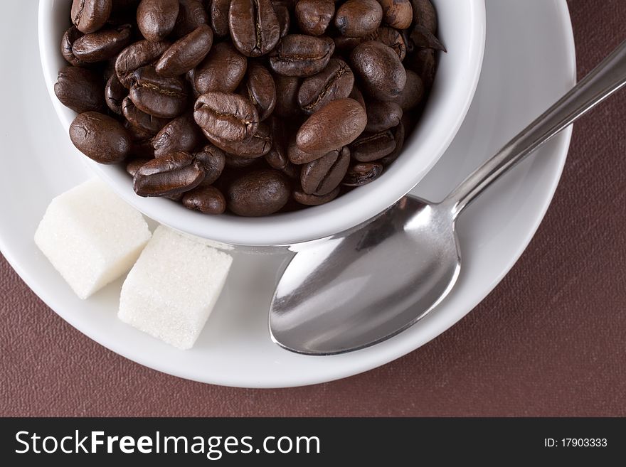 White cup with coffee grains on a brown background