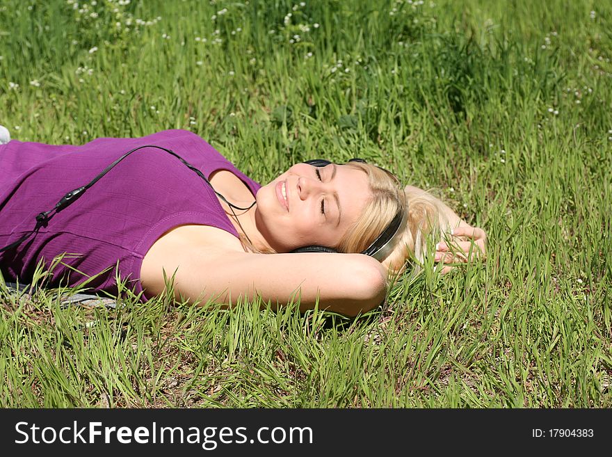 Beautiful young girl with headphones, listen to music on meadow. Beautiful young girl with headphones, listen to music on meadow