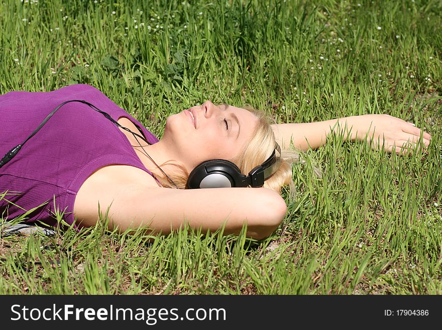 Beautiful young girl with headphones, listen to music on meadow. Beautiful young girl with headphones, listen to music on meadow