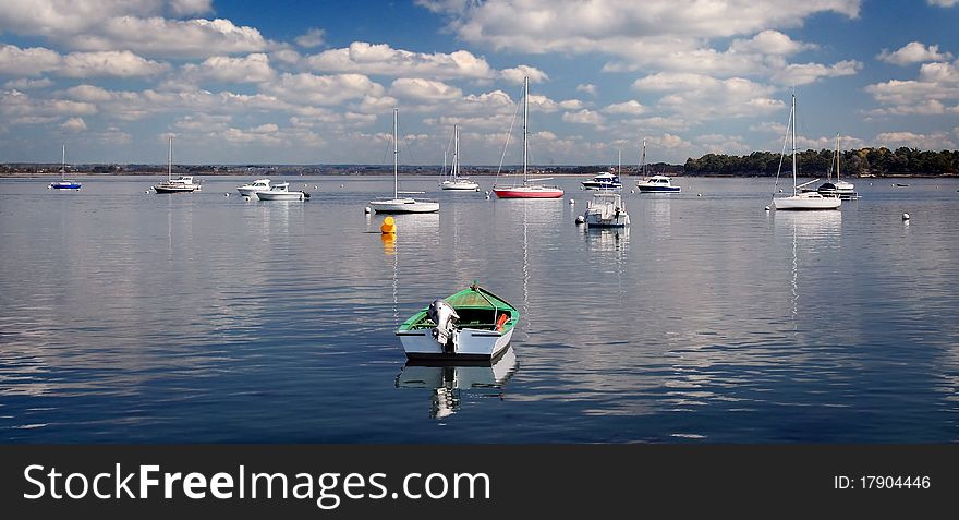 Moored colored boats on the sea under blue sky and smart clouds