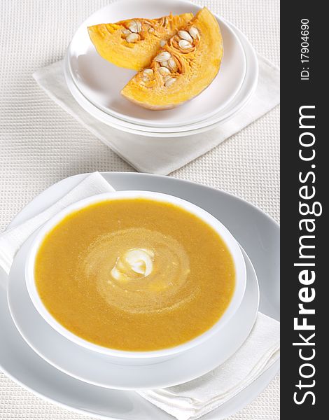 Pumpkin soup in a bowl and two pieces of pumpkin