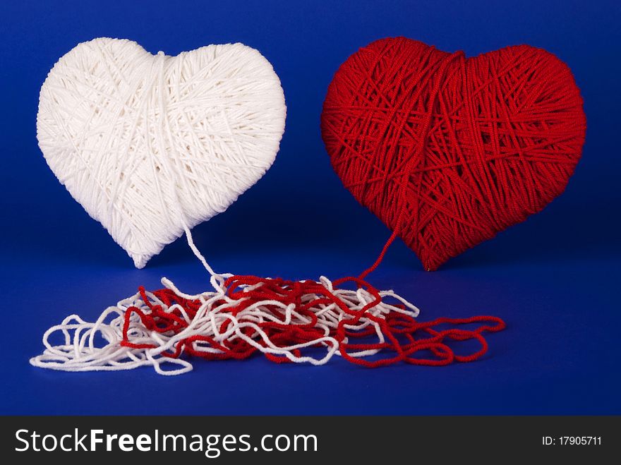 Red and white heart of woolen yarn on a blue background. Valentine's Day.