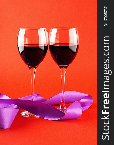 Two glasses of wine on a red background.