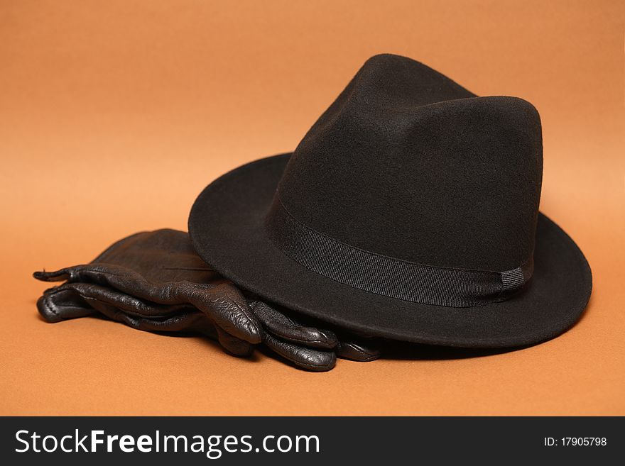 Felt hat and pair of leather gloves on orange background. Felt hat and pair of leather gloves on orange background