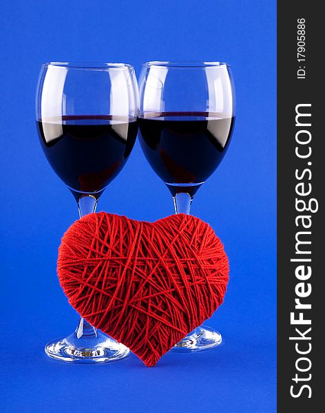 Two glasses of wine and a red heart on a blue background