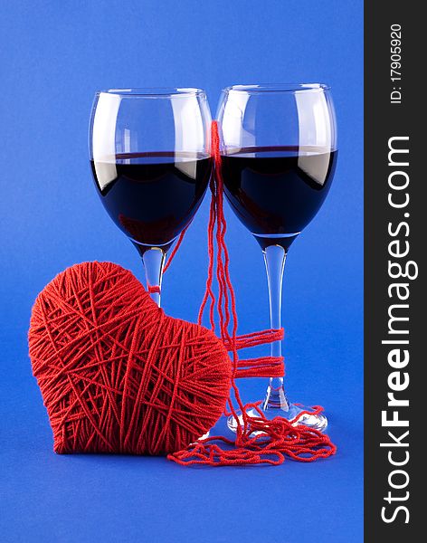 Two glasses of wine and a red heart on a blue