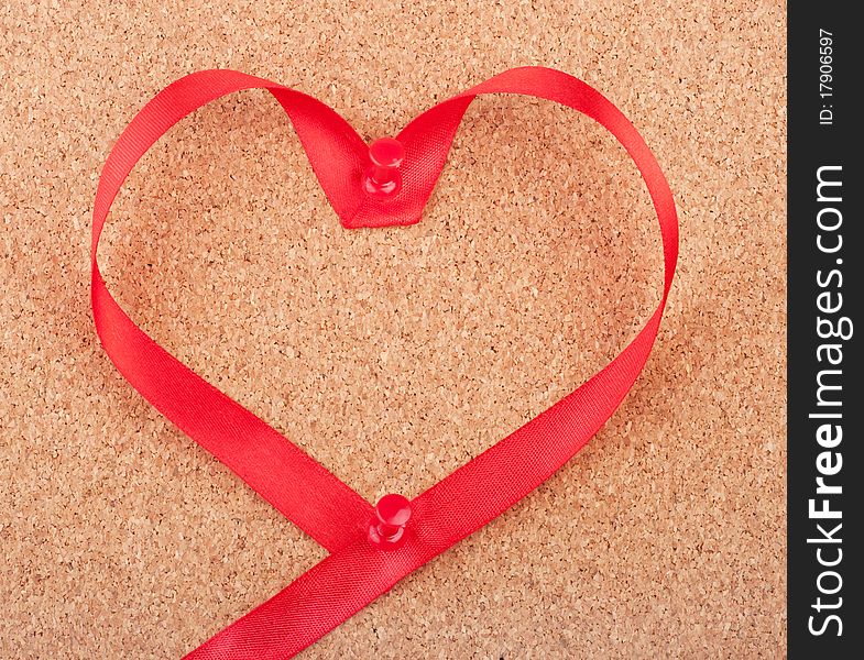 Red heart shaped ribbon pinned to cork board