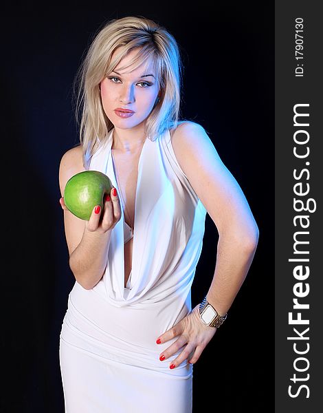 Girl with green apple under blue light against black background