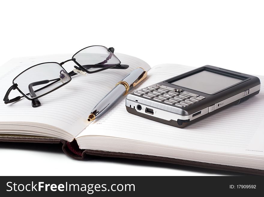 Open diary with a pen, smartphone and glasses on a white background. Open diary with a pen, smartphone and glasses on a white background