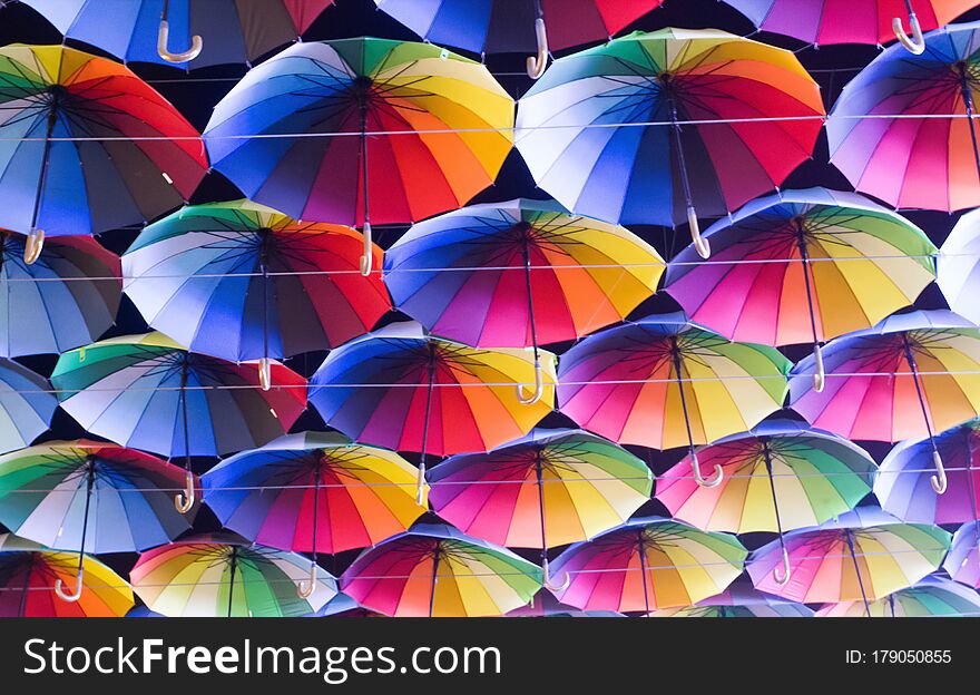 Many colorful umbrellas strung across the street over head