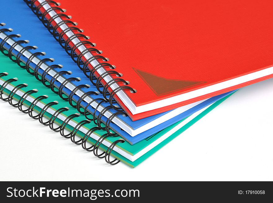 Corner of three color rectangular notebooks on white background.