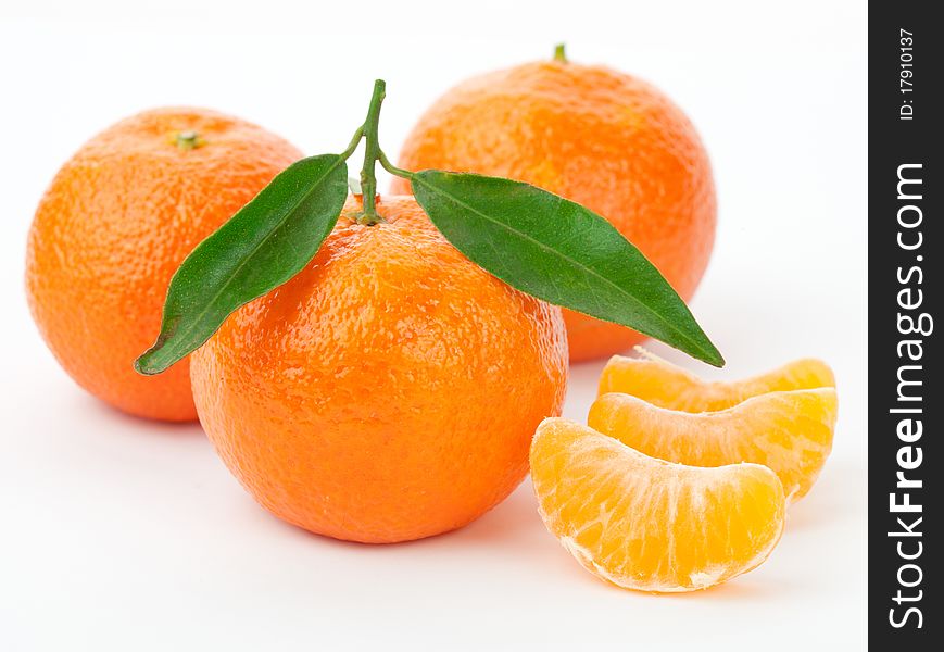 Tangerines with leaves and slices on white background