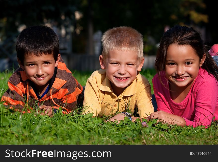 Happy three little friends laying on the grass in the park