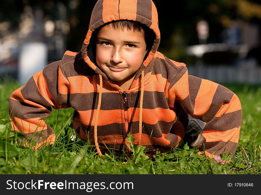 Happy little boy in Sweatshirt laying on the grass in the park