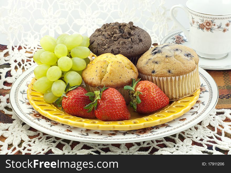 A plate of fresh baked assorted muffins with fresh fruit. A plate of fresh baked assorted muffins with fresh fruit
