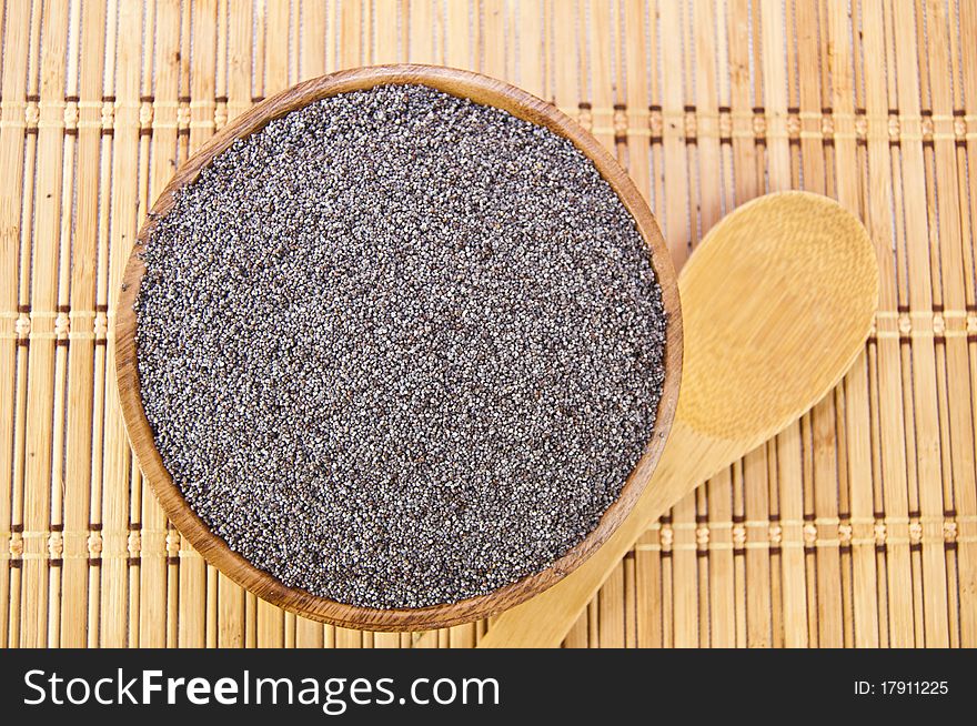 Poppy seeds in a wooden bowl on a table with spoon