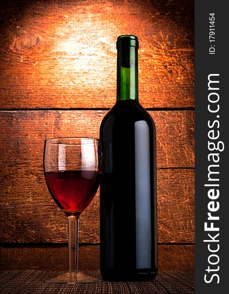 Bottle of red wine and glass on wooden background