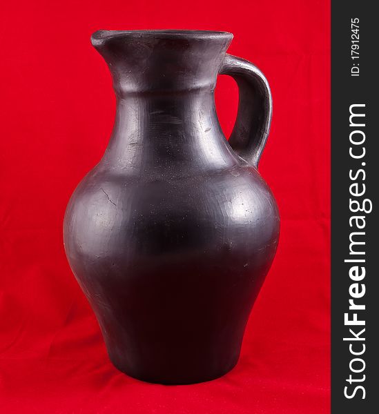 Jjug molded from black clay, on a red background. Jjug molded from black clay, on a red background