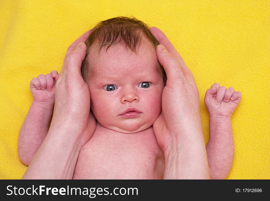 Newborn baby girl over soft yellow towel in mother's hands