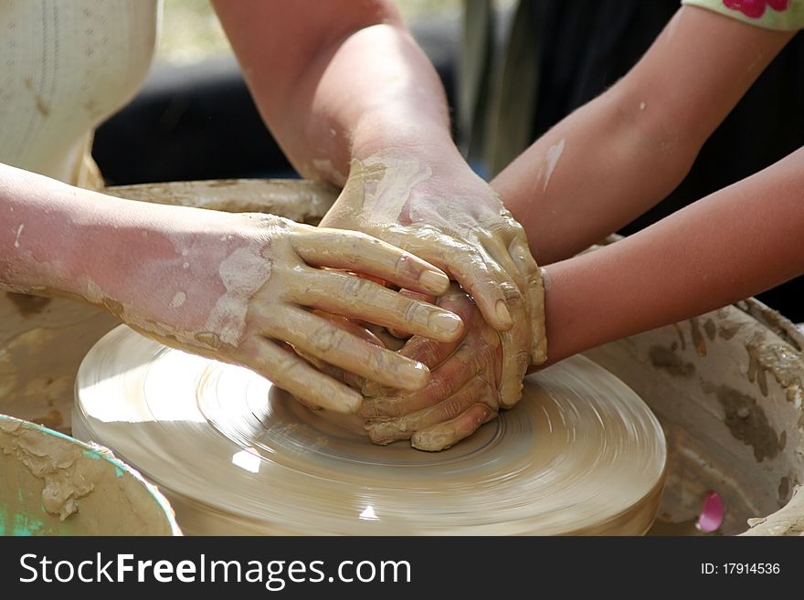 A woman teaches a young girl, that how can she prepares a pot from clay. A woman teaches a young girl, that how can she prepares a pot from clay.