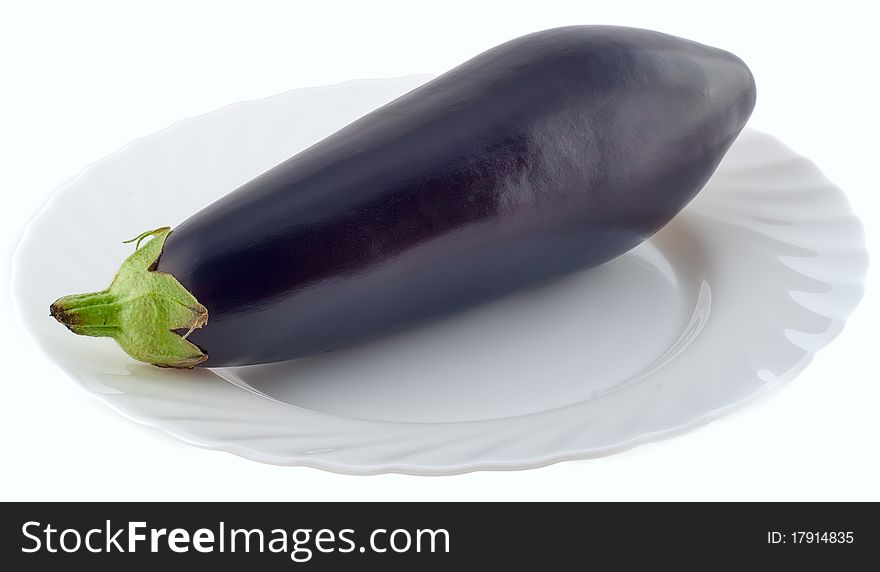 An aubergine on a white plate on white background. An aubergine on a white plate on white background