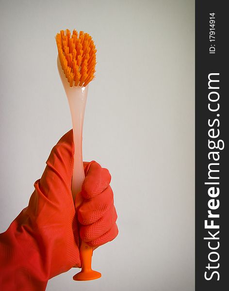 Hand in red rubber glove holding cleaning brush
