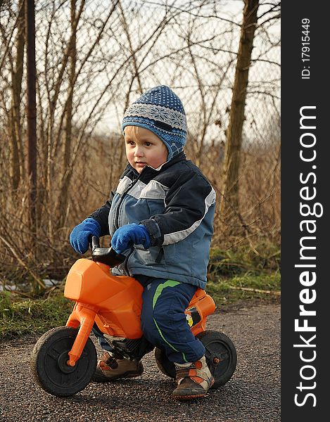 Little boy riding a toy motorbike during an afternoon walk. Little boy riding a toy motorbike during an afternoon walk