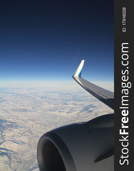 Aerial view of airplane engine and wing over snowy terrain