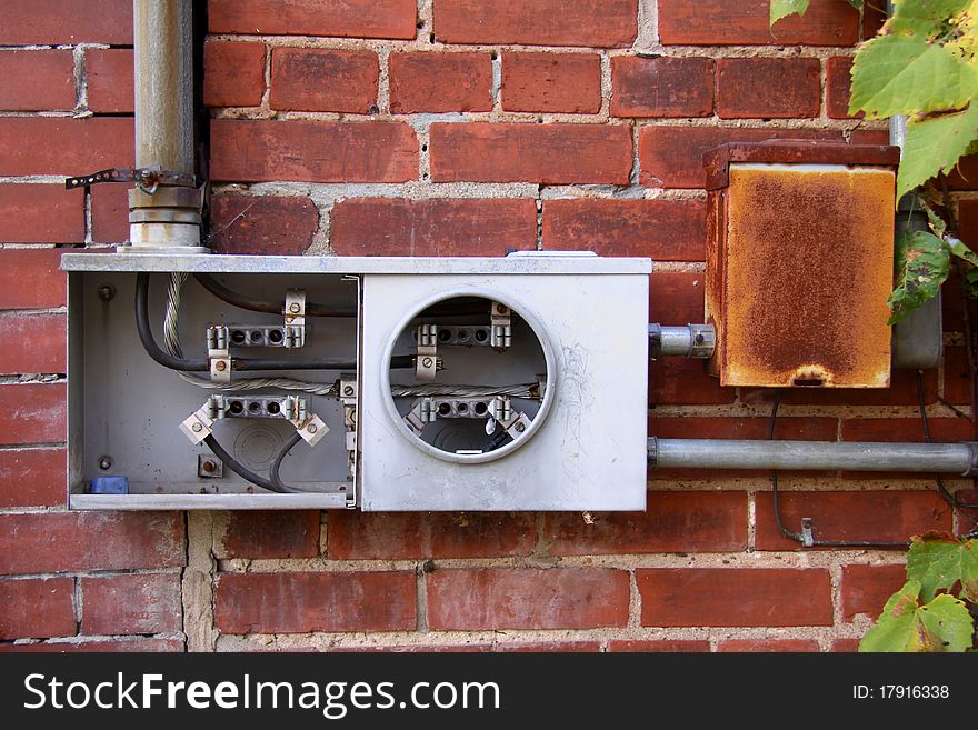 Broken electric meter on a brick wall