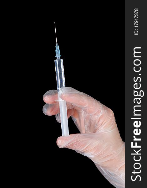 A hand in glove with syringe isolated on black. A hand in glove with syringe isolated on black