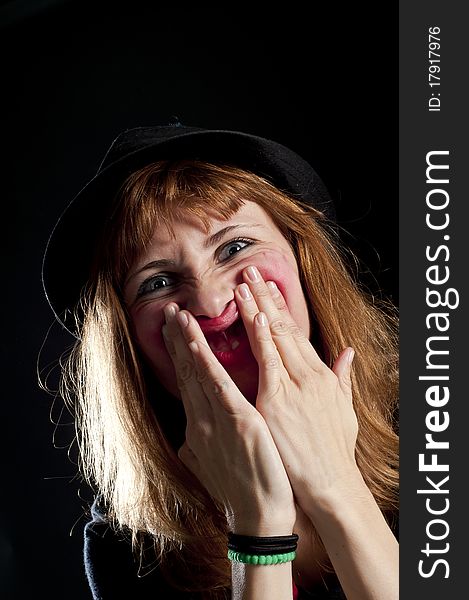 Blonde girl deforms the face with his own hands on black background