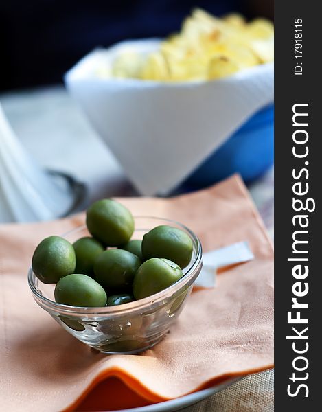 Green olives and chips on bar table