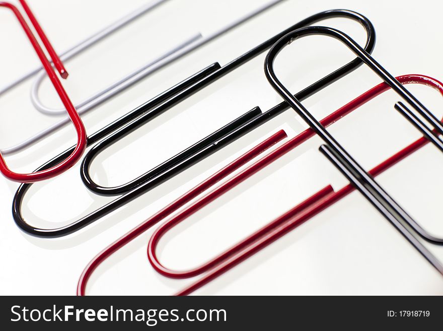 Black, red, and white paper clips sit on top of a desk